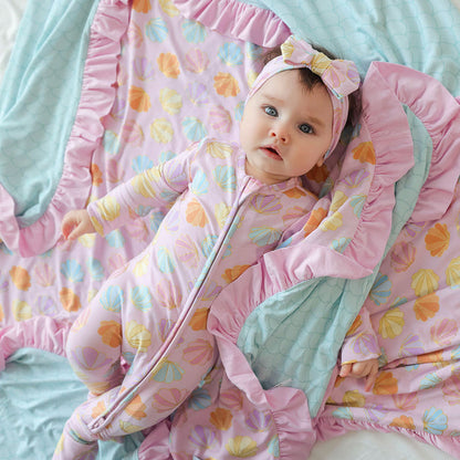 Baby wrapped in a colorful blanket with floral patterns on a light blue background