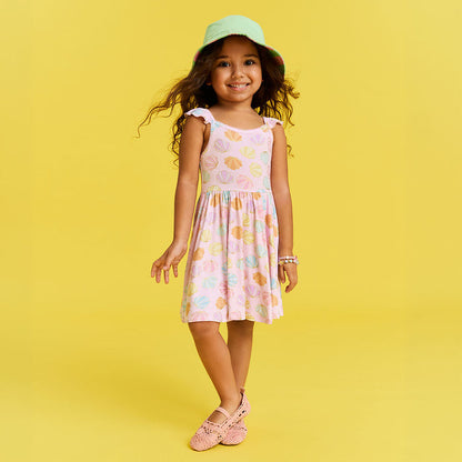 Young girl in a shell patterned dress and hat on a yellow background