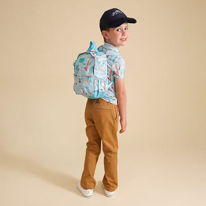 Child wearing a blue backpack and brown pants on a beige background