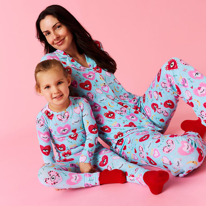 Woman and child wearing matching pajamas with a heart pattern on a pink background