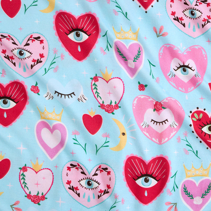 Pattern of hearts with eyes, flowers, and crowns on a blue background