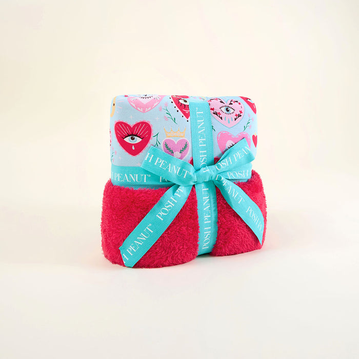 Folded blue and pink blanket with a decorative blue ribbon on a light beige background