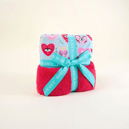 Folded blue and pink blanket with a decorative blue ribbon on a light beige background