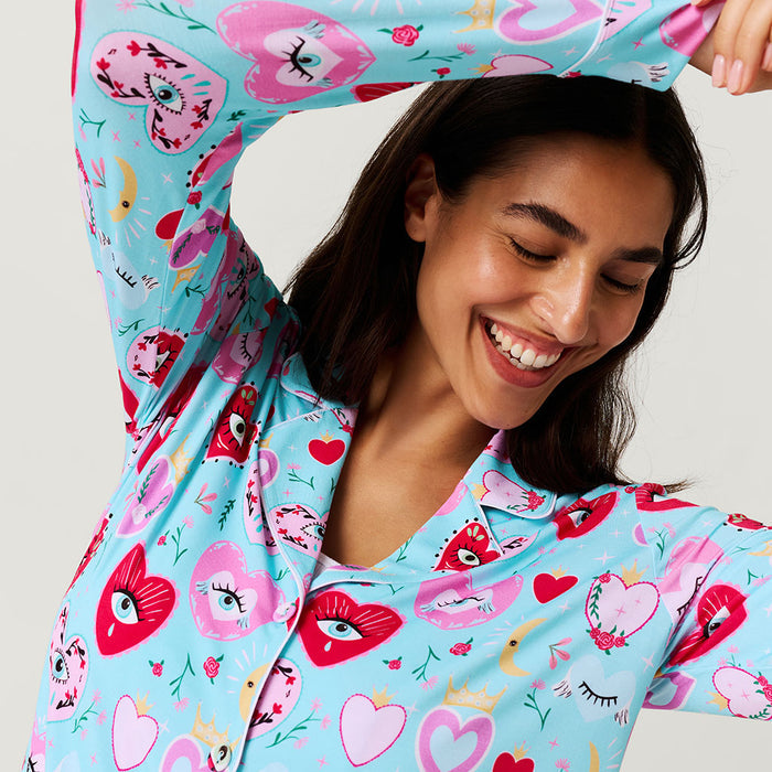 Woman wearing a colorful pajama with heart designs on a plain background