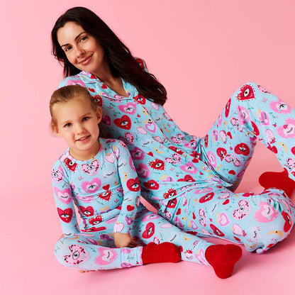 Woman and child wearing matching pajamas with a heart pattern on a pink background