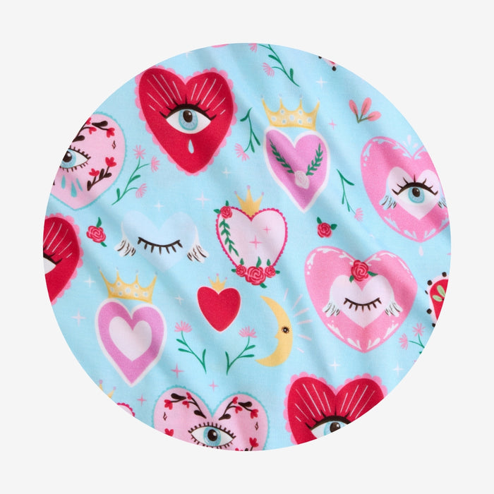 Round fabric swatch with heart and eye pattern on a light blue background