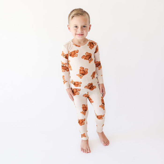 Child wearing a pajama set with teddy bear pattern on a white background