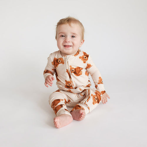 Baby wearing a one piece with fox pattern on a white background