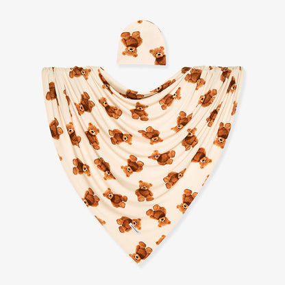 Baby swaddle and beanie set with teddy bear pattern on a white background