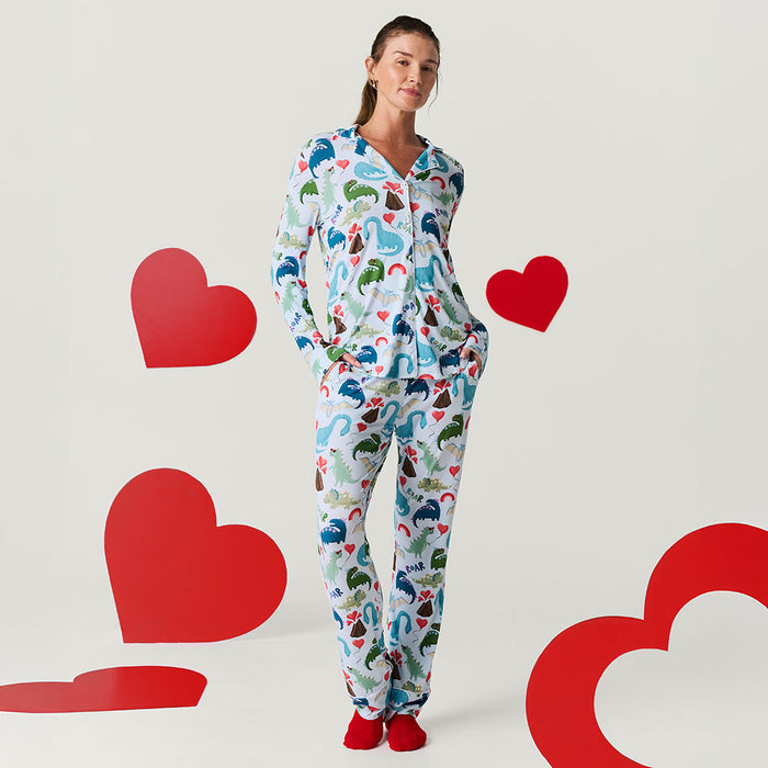Woman wearing a colorful pajama set with dinosaur patterns, surrounded by red hearts on a light gray background.