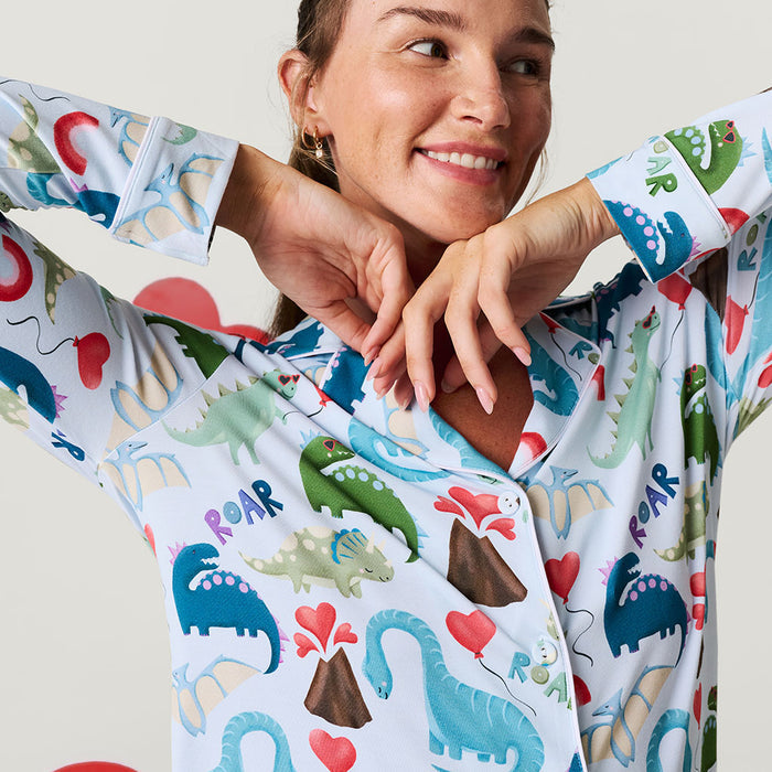 Woman wearing a colorful dinosaur-themed pajama set with a plain background