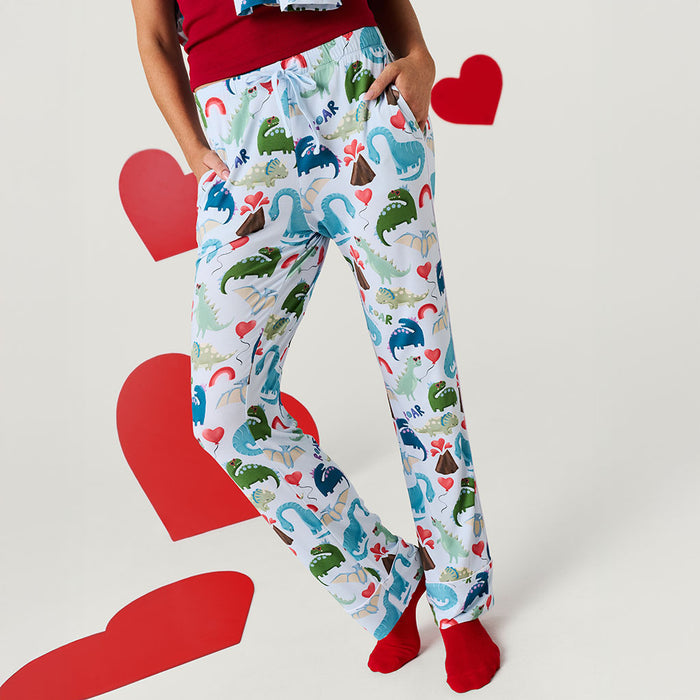 Person wearing colorful dinosaur-patterned pants with red hearts on a light gray background