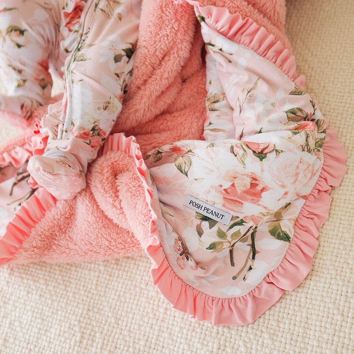 Floral-patterned baby blanket with ruffles and 'Posh Peanut' label on a beige surface