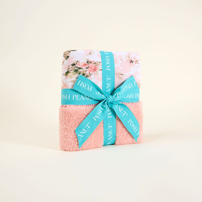 Floral-patterned product wrapped with a pink towel and blue ribbon on a beige background